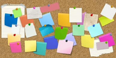 A cork board covered in many different colored sticky notes.