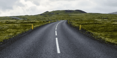 A road with no traffic on it and grass in the background.