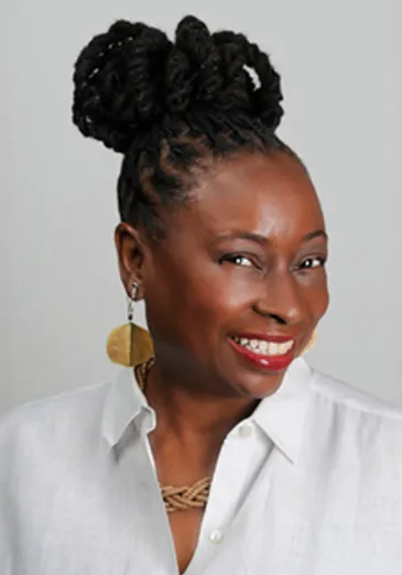 A woman with a bun and earrings smiles.