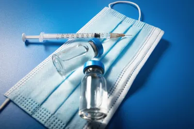 A blue table with a mask and syringe next to it