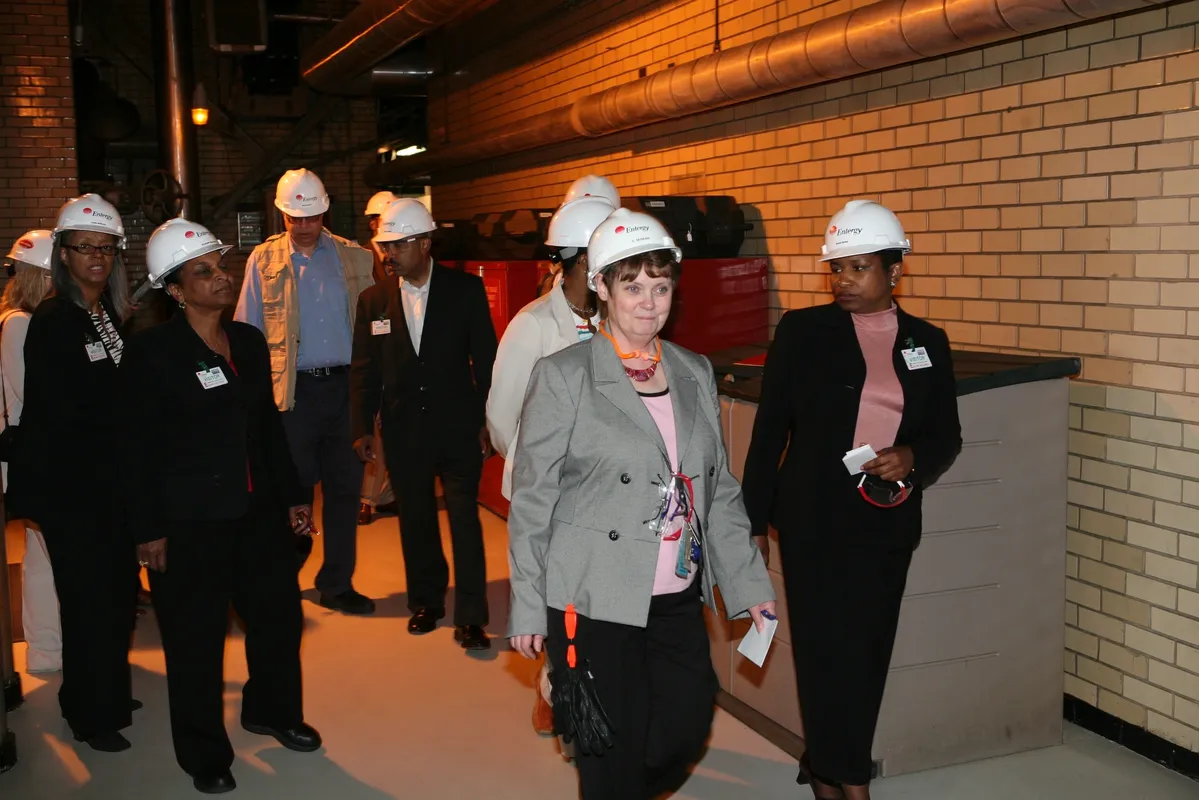 A group of people wearing hard hats and standing in a building.